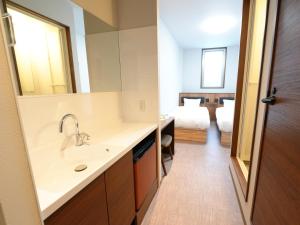 un bagno con lavandino, specchio e letto di HOTEL KANALOA a Tokashiki