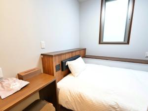 a bedroom with a bed and a desk and a window at HOTEL KANALOA in Tokashiki