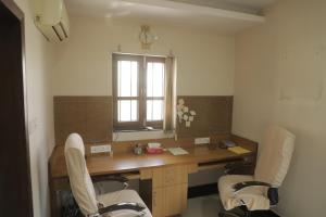 Authentique Home Abode - 3 Bedroom & Living في أودايبور: غرفة مع مكتب مع كرسيين ونافذة