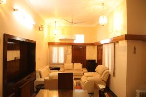 ein Wohnzimmer mit einem Sofa, Stühlen und einem TV in der Unterkunft Authentique Home Abode - 3 Bedroom & Living in Udaipur