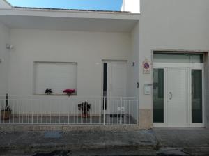 Casa vacanze Cetto e Vera في غالاتينا: مبنى ابيض بباب ونافذة