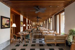 コルカタにあるTaj Taal Kutirのテーブルと椅子、天井ファン付きのレストラン