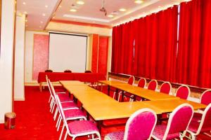uma sala de conferências com cortinas vermelhas e mesas e cadeiras de madeira em Hotel Les Ambassadeurs em Orão