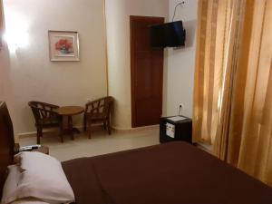 une chambre d'hôtel avec un lit, une table et des chaises dans l'établissement Hotel Les Ambassadeurs, à Oran