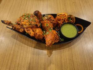 a plate of food with chicken wings and dipping sauce at The Havelock Hotel, Vijay Nagar in Indore