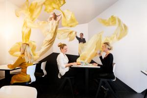 a group of people sitting at a table with a painting at Design Hotel Modez in Arnhem