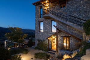 a stone house with stairs on the side at night at Chalet Azanias in Kalavrita