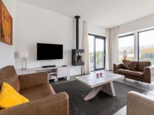 een woonkamer met een bank en een tv bij Brand new luxury villa on a small scale park with its own jetty in Zeewolde