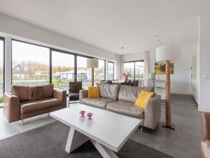 een woonkamer met een bank en een tafel bij Brand new luxury villa on a small scale park with its own jetty in Zeewolde