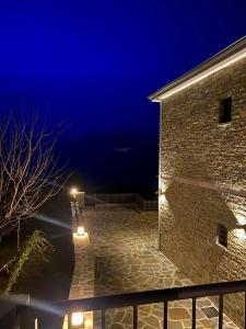 un edificio de ladrillo por la noche con luces encendidas en Monastiri Mountain Escape, en Konitsa