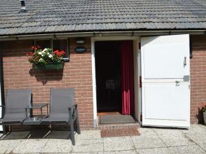 two chairs in front of a brick house with a door at Cozy Holiday Home in Bergen op Zoom with Garden in Bergen op Zoom