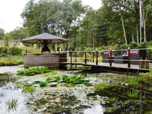 WaterenにあるA detached bungalow with outdoor fireplace covered terrace and pond in a forest plotの池上の木橋