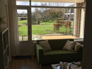 a living room with a green couch in front of a window at Modern Apartment in Noordwijk near the Sea in Noordwijk