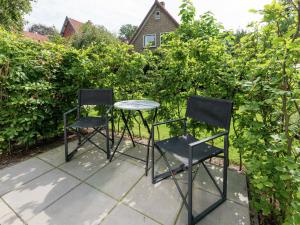 twee stoelen en een tafel voor enkele struiken bij Alluring Apartment in Bergen with Terrace Garden and BBQ in Bergen