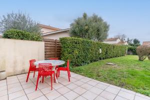 a patio with red chairs and a table and a yard at Gîte Lauréac - Maison avec jardin in Pessac