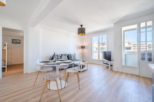 a white living room with a table and chairs at Appartement à 100m de la plage, climatisé in Cagnes-sur-Mer