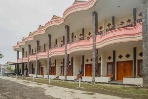 duży budynek z różowo-białą fasadą w obiekcie Pandu Prima Guest House Syariah Mitra Reddoorz w mieście Bandung