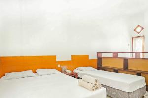 萬隆的住宿－Pandu Prima Guest House Syariah Mitra Reddoorz，一间设有两张床和椅子的房间
