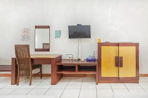 萬隆的住宿－Pandu Prima Guest House Syariah Mitra Reddoorz，客房设有书桌、电视、桌子和椅子。