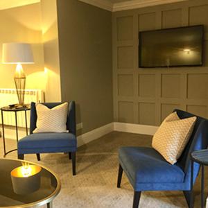 a living room with two chairs and a tv at Rhinefield House Hotel in Brockenhurst