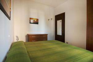 a bedroom with a green bed and a wooden dresser at Appartamenti SA in Follonica