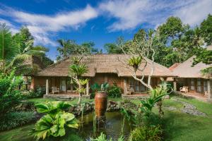 a house with a pond in front of it at De Umah Bali Eco Tradi Home in Bangli
