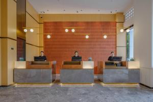 three people sitting at desks in a lobby with their laptops at Atour Hotel Xiamen North Station Jiageng Stadium in Xiamen