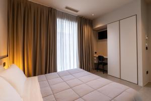 - une chambre avec un grand lit blanc et une fenêtre dans l'établissement Amare Suite & Apartments, à Bellaria-Igea Marina
