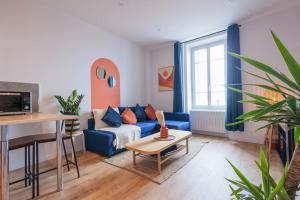 un soggiorno con divano blu e tavolo di Appart Jean Jaurès - 2 min gare - centre ville a Bourg-en-Bresse