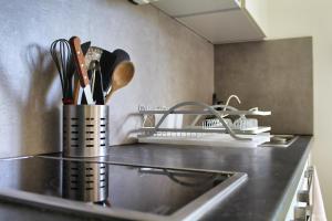 a kitchen counter with two containers of utensils on it at Le Petit Bungalow Créole in Saint-Pierre +30 photos