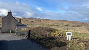 a sign in front of a building in a field at Cleod9 -Croft house at 9 Garenin in Carloway