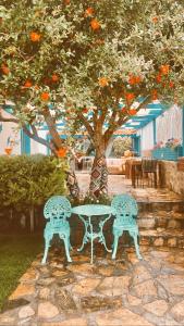 two benches sitting next to a table under an orange tree at Cagla Hotel in Ildır