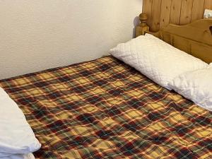 ein Bett mit einer karierten Bettdecke darauf in der Unterkunft La Balcons d olympie in Les Menuires