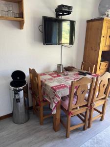 einen Esstisch mit Stühlen und einen TV an der Wand in der Unterkunft La Balcons d olympie in Les Menuires
