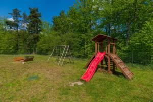 um parque infantil com um escorrega vermelho e um baloiço em Peaceful house with sauna em Nowe Czaple