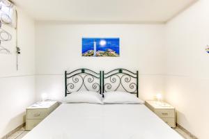 1 dormitorio blanco con 1 cama y 2 mesitas de noche en Dei Bleve - Leucos, en Castrignano del Capo