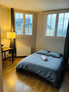 een slaapkamer met een bed, een bureau en ramen bij Superbe Duplex pour 8/10 personnes in Rouen