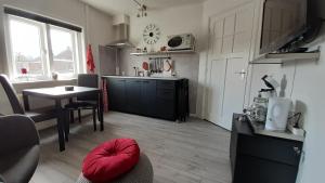 een keuken en eetkamer met een tafel en een rood kussen bij Boxtel, Appartement (1-4p) nabij station/centrum in Boxtel