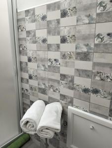 a bathroom with two towels and a tiled wall at Casa Rosa 