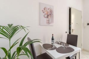 a white dining room with a table and a plant at Casa Regina 2, nel centro storico di Alba! in Alba +8 photos