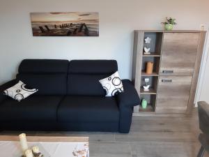 a living room with a black couch and a shelf at Ferienwohnung Nordsee in Pewsum