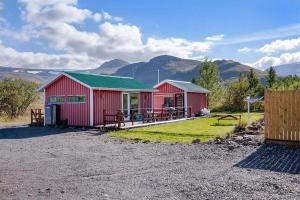 a red building with a green roof with mountains in the background at Sólvellir Holiday Home in Kjósahreppur
