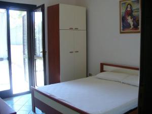 a bedroom with a white bed and a cabinet at Accogliente Appartamento a pochi passi dal mare in Funtana Meiga