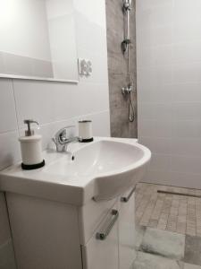 a white sink in a bathroom with a shower at Domek Mikołajki in Mikołajki +16 photos