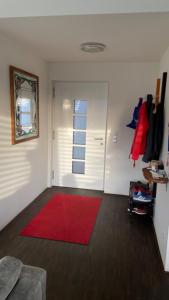 a living room with a red rug and a door at Ferienhaus Rolf in Peterswald-Löffelscheid