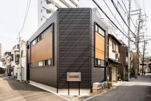 a black building on the side of a street at Fully furnished house for families with infants. in Osaka