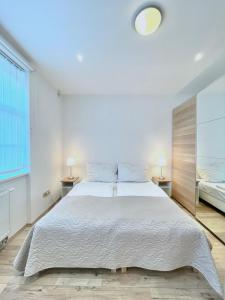 a bedroom with a large white bed with two lamps at Apartment in Center of Prague with balcony in Prague