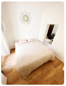 - une chambre avec un lit blanc et un mur blanc dans l'établissement L'Ambre, à Angers