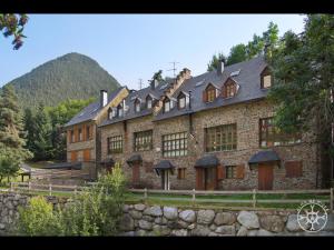 a large brick building with a stone wall at CASA DEL VALLE de Alma de Nieve in Tredós