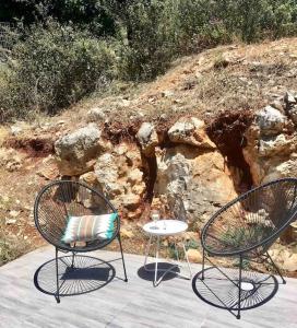 dos sillas y una mesa delante de algunas rocas en Villa Belam, entre montagne et mer, en Kambiá